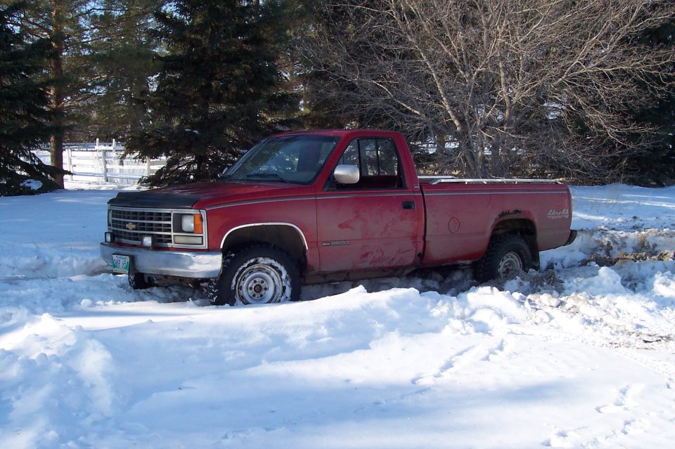 Red Chevrolet pickup parked in snow with a bowtie grille emblem