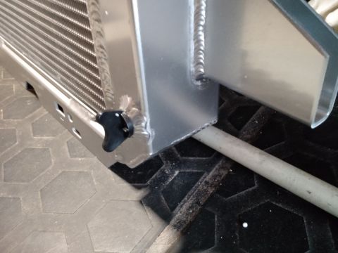 1992 Ford Bronco - Close-up of an aluminum radiator part with a black knob and visible welds.