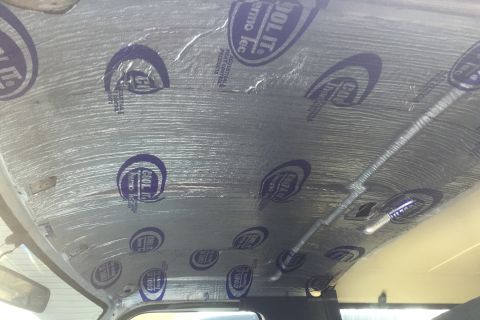 1995 Ford Bronco - The interior of a vehicle shows the headliner being covered with sound and heat insulation material.