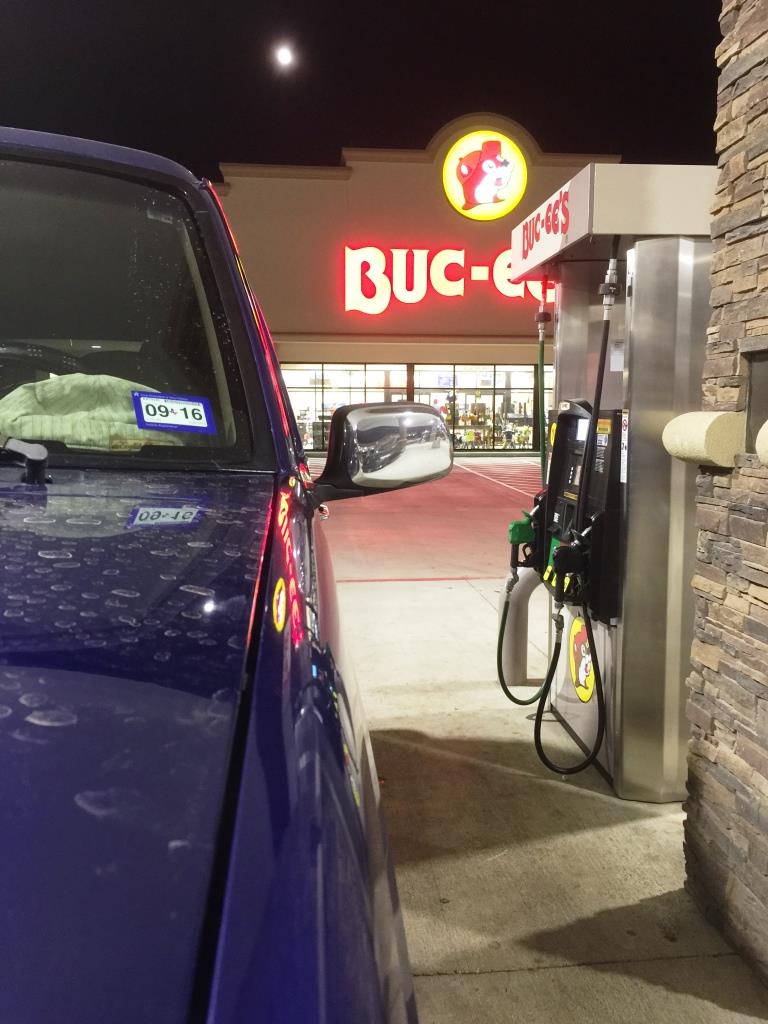 Blue SUV parked at a Buc-ee's gas pump at night