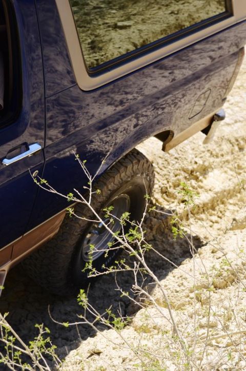 1996 Ford Bronco - A dark blue SUV with a chrome door handle and brown trim is stuck in sandy terrain.