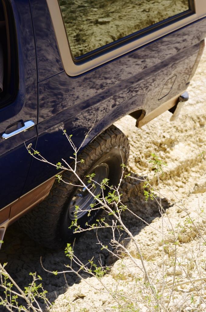 Dark blue SUV with chrome door handle and brown trim, stuck in sand