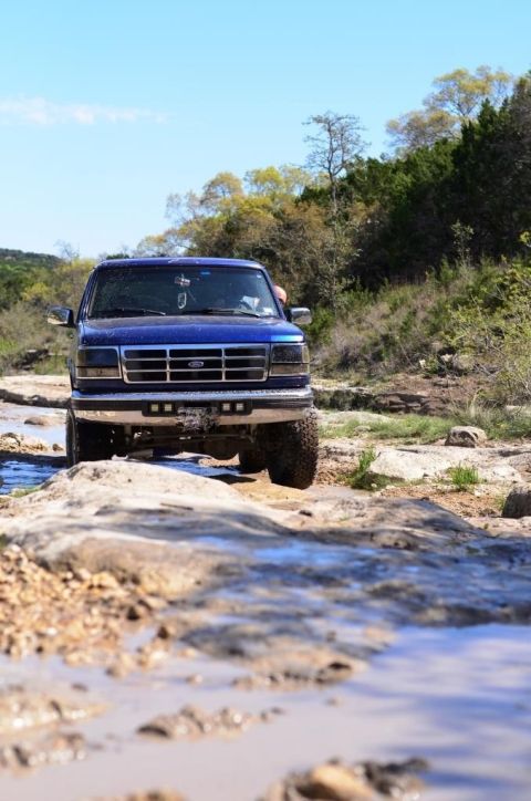1996 Ford Bronco - 1996 Ford Bronco navigating a challenging off-road course with water and rocks.