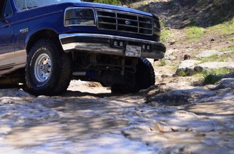 1996 Ford Bronco - Blue 1996 Ford Bronco navigates a rocky, wet trail.