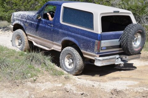 1996 Ford Bronco - This 1996 Ford Bronco navigates a rough, off-road trail, covered in dust and mud.