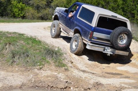 1996 Ford Bronco - This 1996 Ford Bronco is navigating a challenging off-road trail with steep inclines and loose dirt.