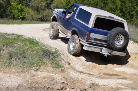 1996 Ford Bronco - A blue and tan Ford Bronco navigates a challenging off-road trail.