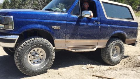 1996 Ford Bronco - Blue 1996 Ford Bronco with tan trim and aftermarket wheels driving off-road.