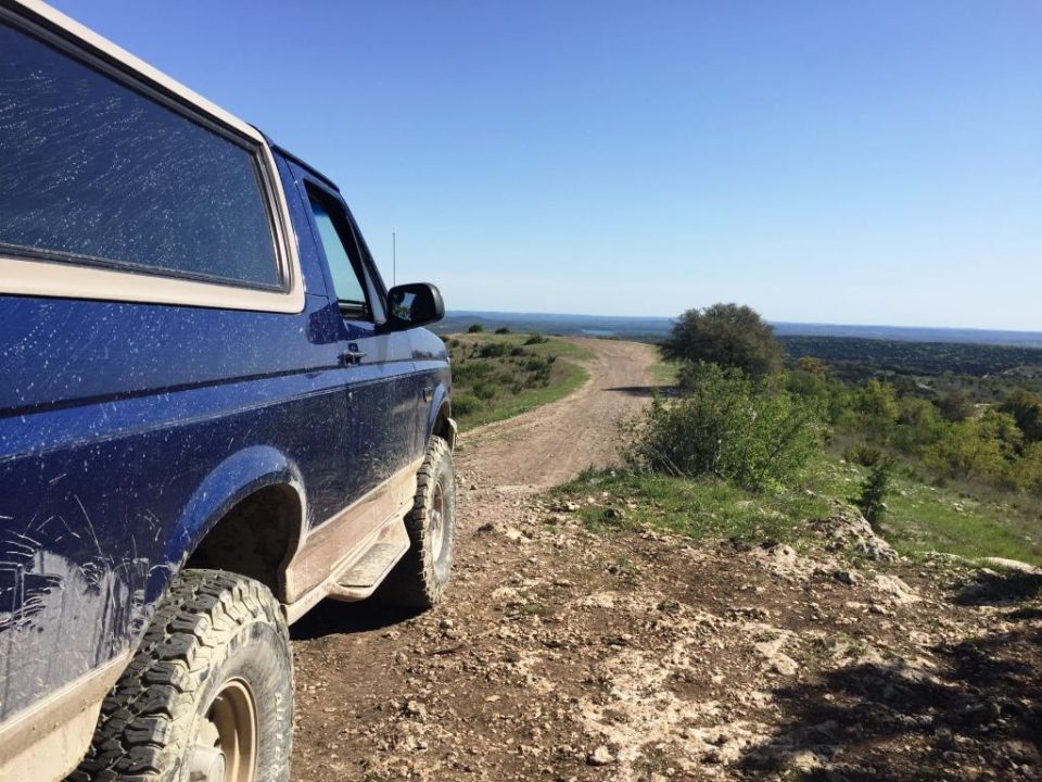 Blue SUV parked on a dirt road overlooking a valley