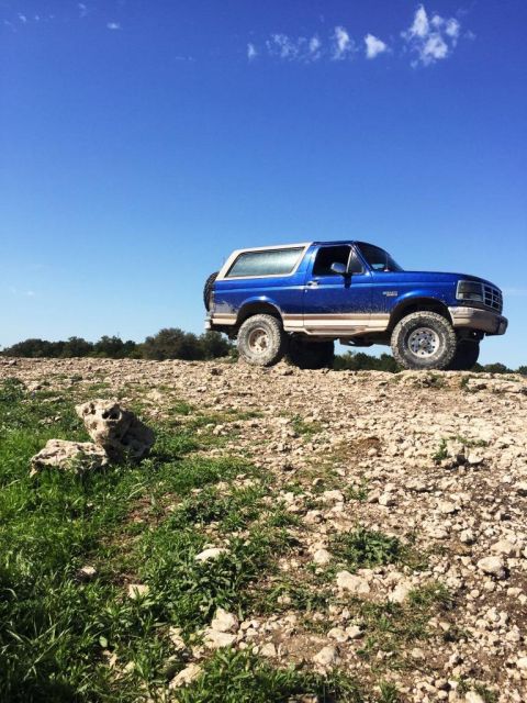 1996 Ford Bronco - 1996 Ford Bronco parked on a rocky hill with a clear blue sky overhead.