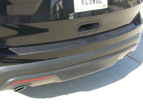 2016 Ford Explorer - Rear view of a black 2016 Ford Explorer, showing the bumper, tow hitch cover, and exhaust pipe.