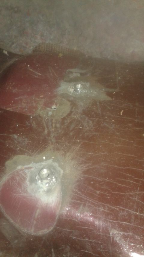 1996 Ford Bronco - Close-up of a damaged red car body panel with visible bolts.