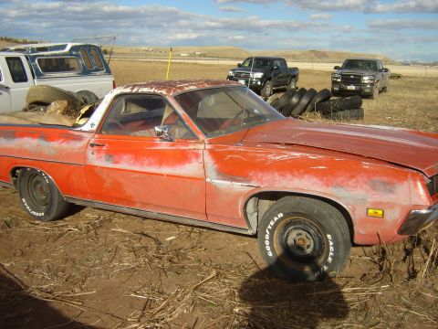 1971 Ford Ranchero - This weathered orange 1970 Ford Ranchero sits in a dusty lot with other vehicles.