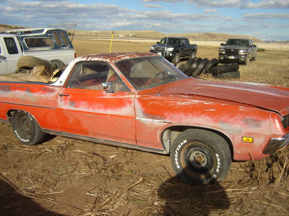 Orange 1970 Ford Ranchero with rust and dents, viewed from the front-right