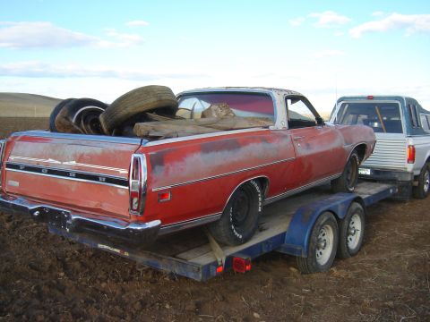 1971 Ford Ranchero - A red Ford Ranchero, likely a 1970 model, is being transported on a trailer behind a pickup truck.