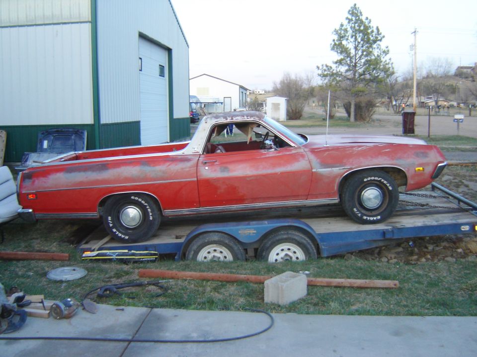 Red pickup truck on a trailer, parked outside a building