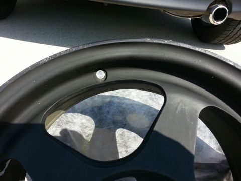 2010 MINI Cooper - A close-up shot focuses on a car's wheel and exhaust pipe, with the vehicle's bodywork visible above.