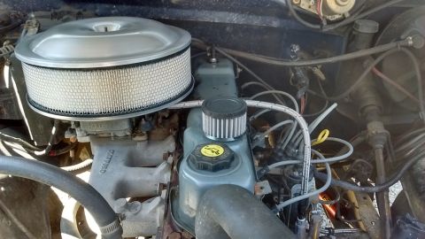 1985 Ford Bronco - Close-up view of an engine bay, showing the carburetor, air filter, and various engine components.