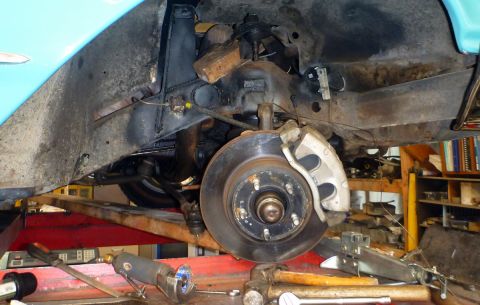1964 Mercury Monterey - Close-up view of the front suspension and brake system of a vehicle undergoing service.
