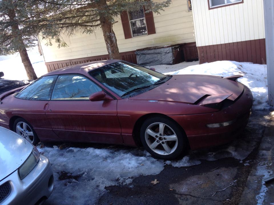 Maroon 1995 Ford Probe with pop-up headlights parked on a snowy driveway.