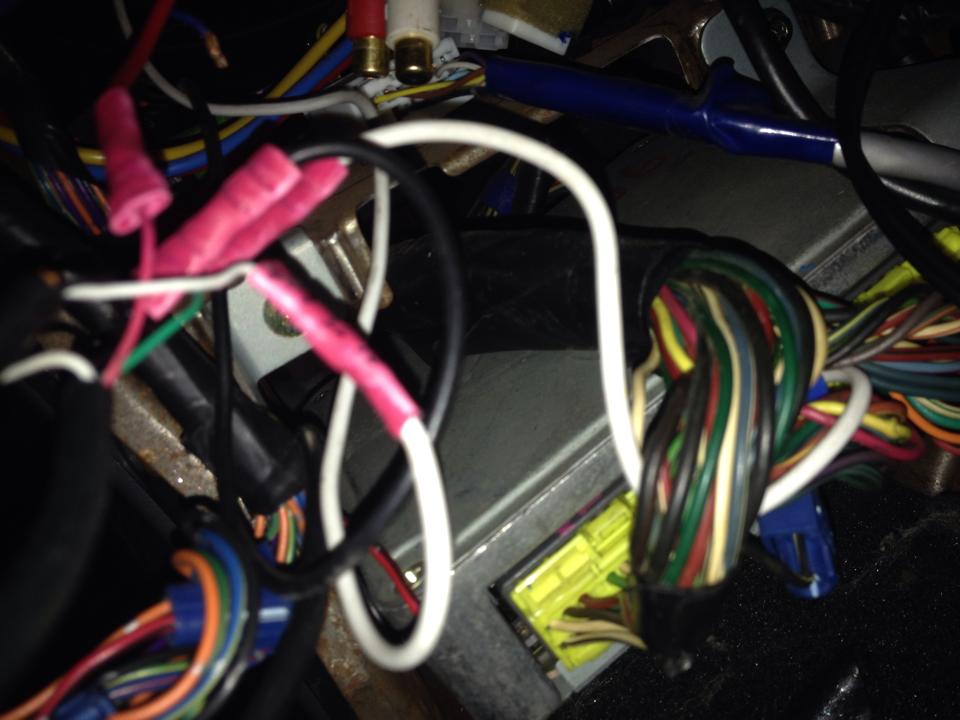 Close-up of automotive wiring harness with pink connectors and electronic modules.