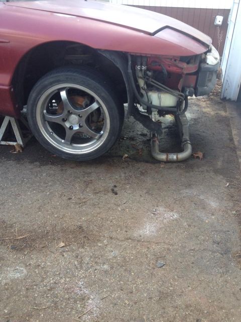 1995 Ford Probe - A red Ford Probe is shown from the front quarter angle with the front bumper and passenger side headlight removed. The vehicle is supported…