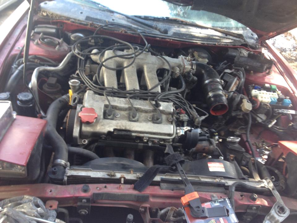 1995 Ford Probe engine bay with hood open, V6 engine, hoses, wires, fuse box
