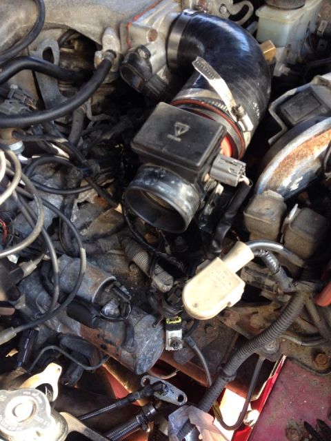 1995 Ford Probe - Engine compartment detail showing a mass air flow sensor, intake hose and wiring harness.