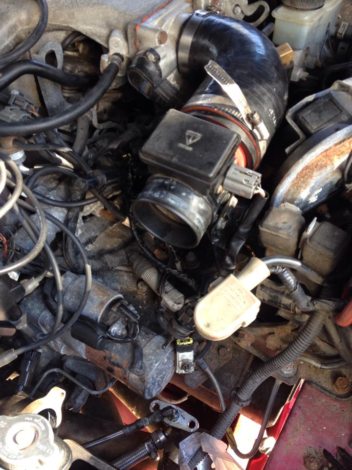 Engine bay close-up of mass air flow sensor and intake hose with clamps