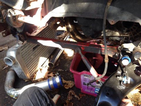 1995 Ford Probe - A close-up view of car parts, including an intercooler, exhaust piping, and suspension components, laid out on the ground with fallen leave…