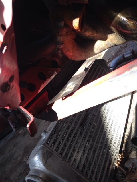 1995 Ford Probe - A close-up view of a vehicle's intercooler and surrounding engine components, featuring a red bracket and metallic piping.
