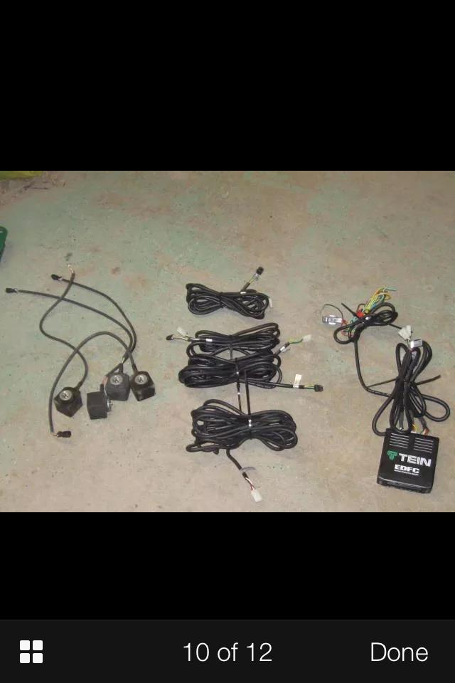 Bundles of wiring harnesses and TEIN EDFC control box on concrete.