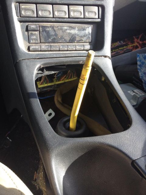 1995 Ford Probe - Interior view of a car's center console with the gear shift lever removed, revealing exposed wiring and components. The dashboard features…