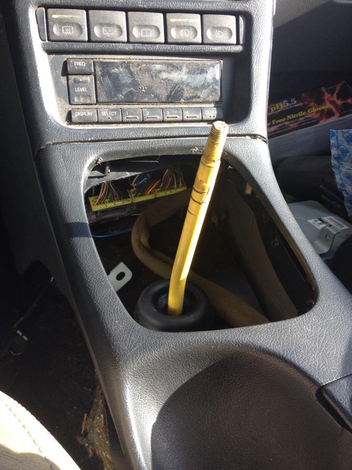 Car interior center console with exposed wires and dusty dashboard buttons.