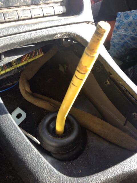 1995 Ford Probe - A close-up interior shot shows a yellow gear shift lever protruding from a black rubber boot in the center console of a vehicle. Wires and…