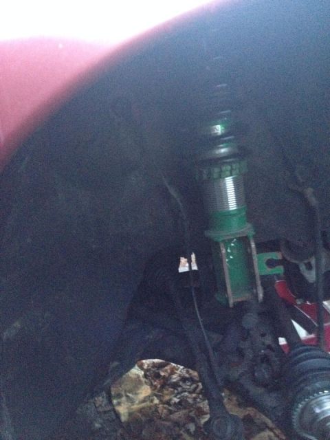 1995 Ford Probe - A close-up view of the front suspension of a vehicle, featuring a green adjustable coilover shock absorber. The vehicle's fender and part o…