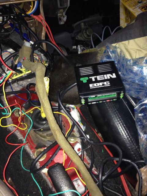 1995 Ford Probe - A close-up view of a black TEIN EDFC controller unit with green lettering, installed amongst a complex wiring harness in a vehicle's interi…