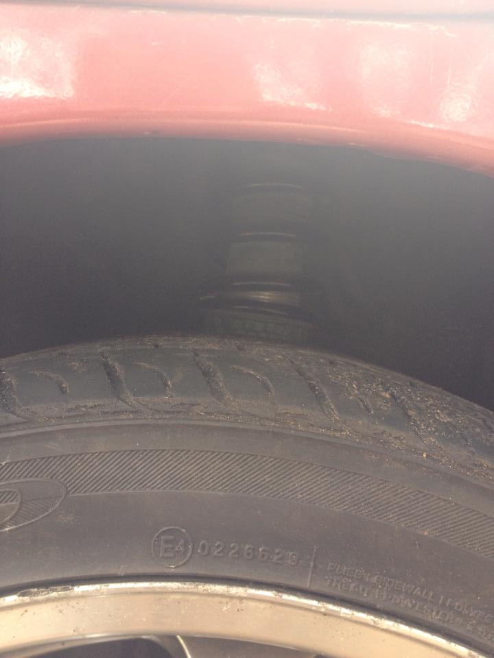 Close-up of a red vehicle's front tire and suspension. E4 0226629 marking visible.