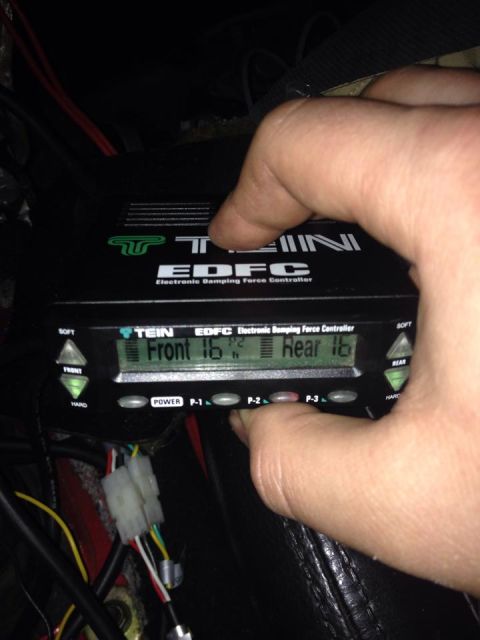 1995 Ford Probe - A hand presses the P-2 button on a TEIN EDFC Electronic Damping Force Controller, which displays settings for the front and rear suspension.