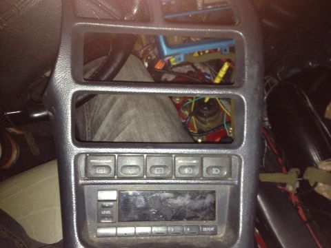 1995 Ford Probe - A close-up view of the center console of a car, showing the radio, several buttons, and exposed wiring in the upper compartments.