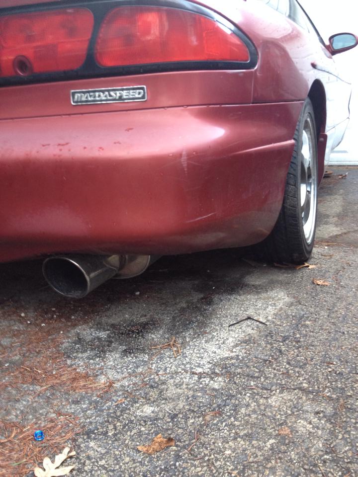 Red MazdaSpeed car rear passenger side with chrome exhaust tip.