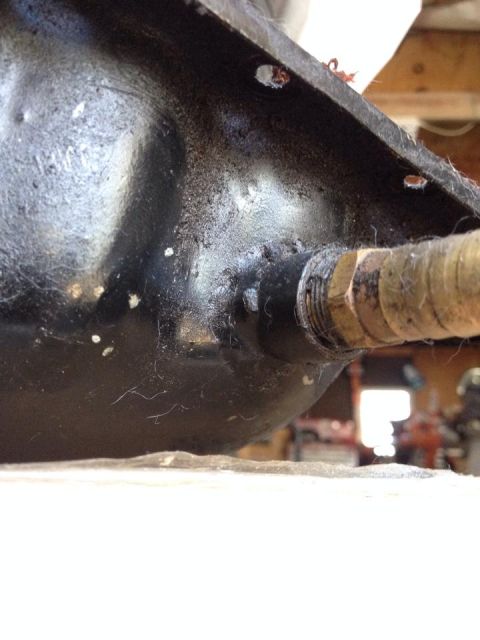 1995 Ford Probe - Close-up view of a black metal part, possibly an oil pan, with a threaded brass fitting attached. The surface shows some wear and is covere…