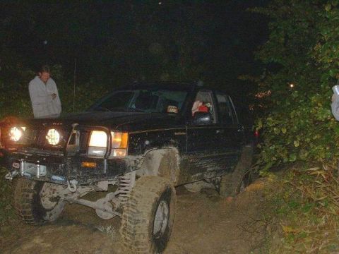 1978 Ford Bronco - A black SUV navigates a muddy trail at night, equipped with auxiliary lights and an off-road bumper.