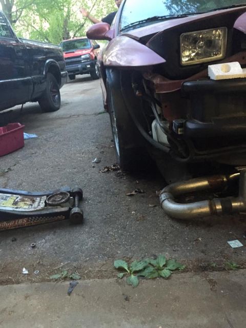 1995 Ford Probe - A low-angle shot of the front passenger side of a purple 1995 Ford Probe. The car is parked on an asphalt surface next to a black pickup tr…