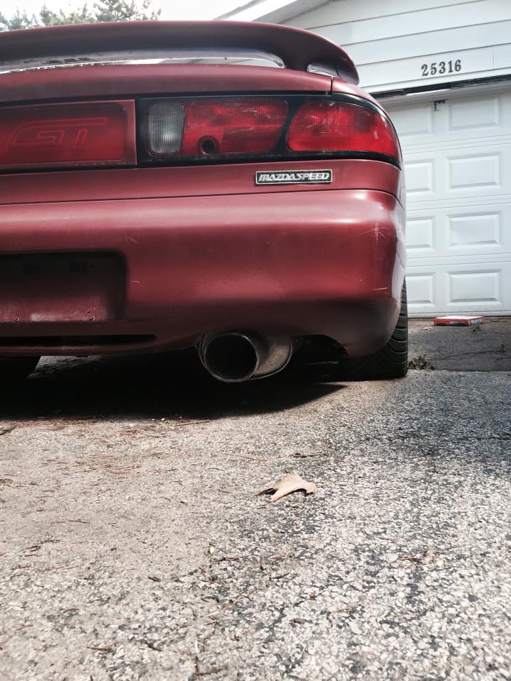 Rear view of a red MazdaSpeed car with a spoiler and visible exhaust pipe.