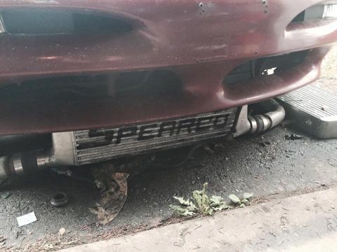 1995 Ford Probe - A front view of a custom intercooler installed on a dark red vehicle, visible below the front bumper. The intercooler has the word "SPEARCO…