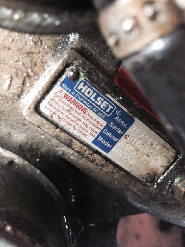 Holset turbocharger identification plate with warning and model/serial numbers.