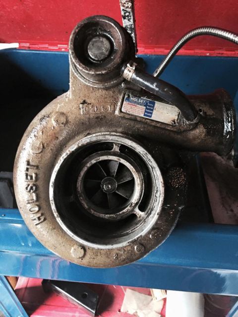 1995 Ford Probe - A close-up, slightly angled view of a used Holset turbocharger, showing the turbine wheel and housing. A metal tag with the Holset logo and…