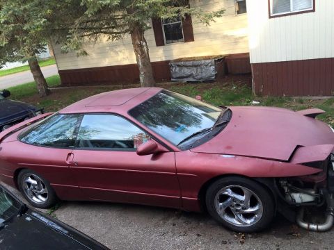 1995 Ford Probe - A maroon 1995 Ford Probe is parked on a gravel driveway in front of a house. The front passenger side fender and bumper are missing, exposi…