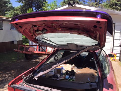 1995 Ford Probe - The open trunk and rear hatch of a red coupe are visible, with the trunk containing various items and the hatch revealing the interior and…